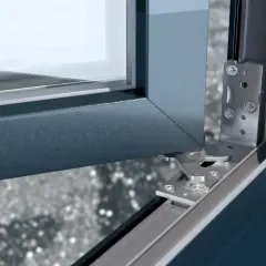 Mechanizm drzwi balkonowych nie chce się zamknąć. Widoczny metalowy zawias i fragment ramy okiennej.