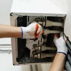 Instalator podłącza rury do nowego pieca gazowego. Pamiętaj, co ile lat wymiana pieca gazowego jest zalecana dla bezpieczeństwa.