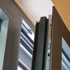 Mechanizm okna się nie uchyla. Widoczny detal nowoczesnego okna z szarym profilem i metalowym zamkiem.