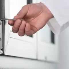 Dłoń z kluczem imbusowym wykonuje regulację okna góra dół, dostosowując zawias.