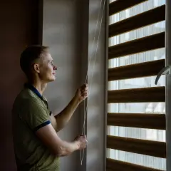 Mężczyzna reguluje rolety dzień-noc, pokazując różne rodzaje rolet.