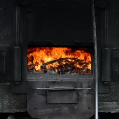 Piec kaflowy z płonącym drewnem. Czas na wymianę pieca na wsi? Zastanów się nad nowoczesnymi rozwiązaniami.