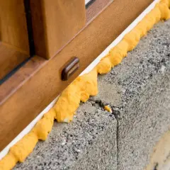 Pianka montażowa przy oknie. Zastanawiasz się, czym zmyć piankę montażową z okna? Ten obrazek pokazuje problem.