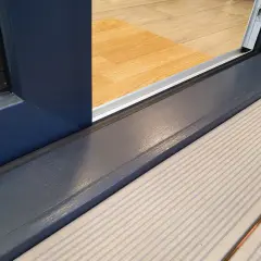 Szary próg okna HS z ciemnoniebieską ramą, widoczny od strony tarasu.