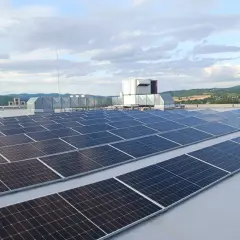 Duże panele fotowoltaiczne na dachu, obok systemów wentylacyjnych i agregatu prądotwórczego, zapewniające niezawodność energetyczną.