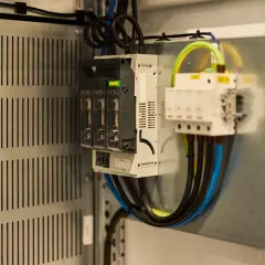 Wnętrze szafy elektrycznej z bezpiecznikami i przewodami. Sprawdź, jak sprawdzić czy falownik działa, analizując połączenia i wskaźniki.