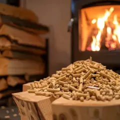 Stos drewna i pelletu przed paleniskiem z płonącym ogniem.