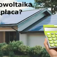 Dom z panelami fotowoltaicznymi na dachu, obok kalkulator, sugerujący opłacalność fotowoltaiki.