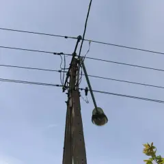 Słup energetyczny z wiszącą lampą uliczną, gdzie mogło dojść do kradzieży prądu. Policja bada sprawę.