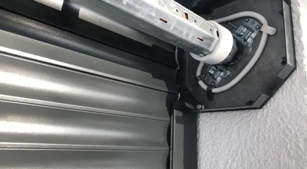 Naprawa żaluzji zewnętrznych: widok mechanizmu silnika i zwiniętego pancerza.