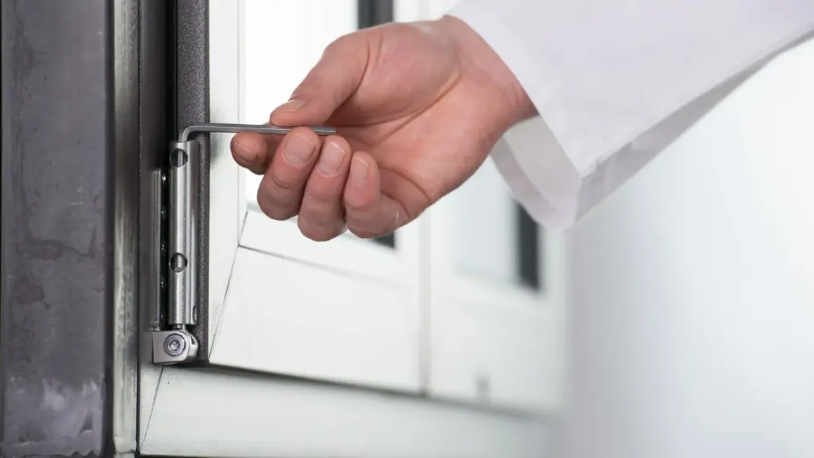 Dłoń z kluczem imbusowym wykonuje regulację okna góra dół, dostosowując zawias.