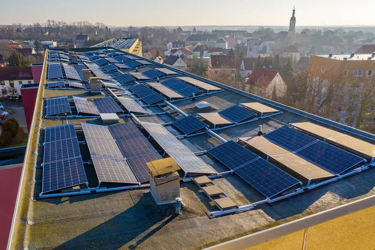 Panele fotowoltaiczne na dachu bloku mieszkalnego, zapewniające zieloną energię dla wspólnot mieszkaniowych.