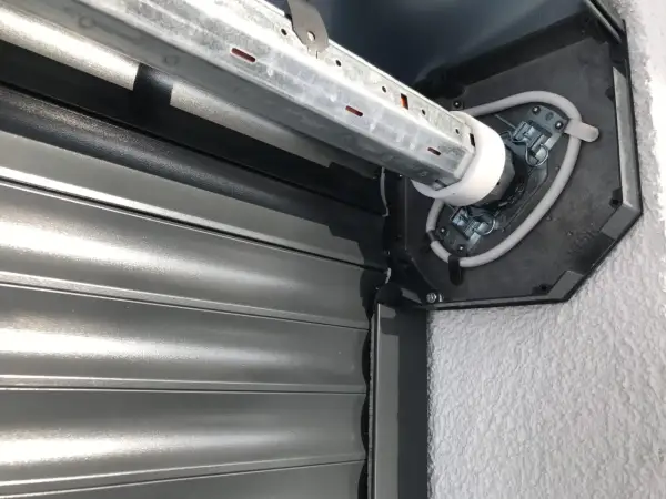Naprawa żaluzji zewnętrznych: widok mechanizmu silnika i zwiniętego pancerza.