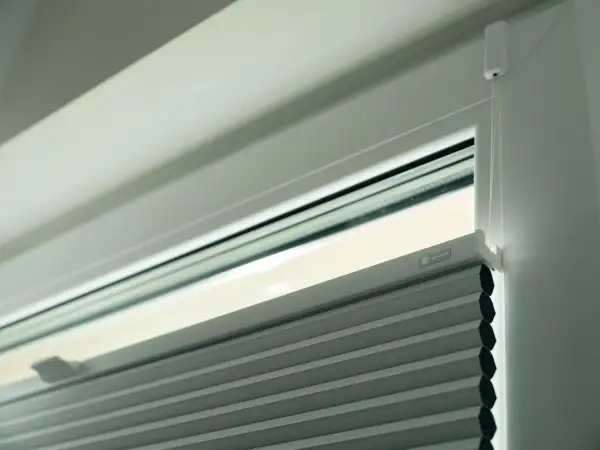 Nowoczesne rodzaje rolet plisowanych z systemem sznurkowym, dyskretnie zamontowane w oknie.